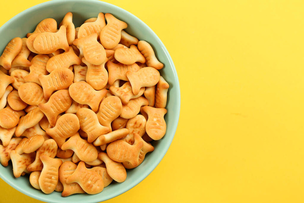 Delicious goldfish crackers in bowl on yellow background, top view. Space for text - Foto, Bild