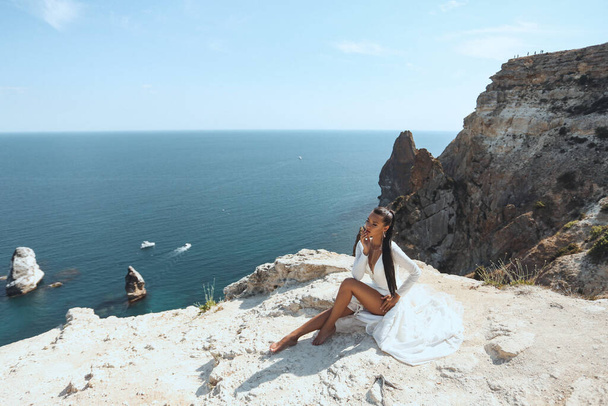 fashion outdoor photo of beautiful woman with dark hair in luxurious wedding dress and accessories posing in beautiful landscape - Foto, Imagen