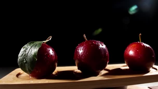 Dřevěný stojan se sladkými zralými švestkami na tmavém pozadí - Záběry, video
