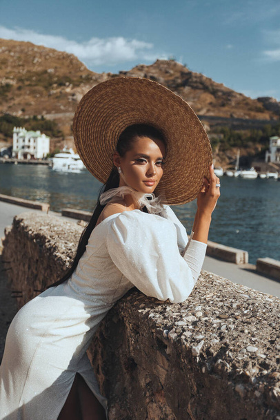 fashion outdoor photo of beautiful woman with dark hair in luxurious wedding dress and accessories posing in beautiful landscape - Zdjęcie, obraz
