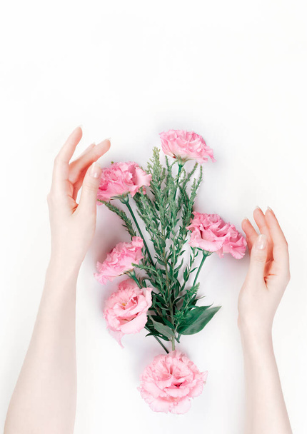 Delicate female hands frame the scattered pink buds of eustoma. White background. Flat lay. The skin is albino. Copy space. The concept of Floristics and tenderness. - Foto, immagini