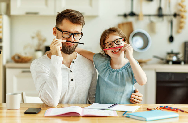 Cheerful schoolgirl with dad wearing similar eyeglasses having fun and looking at camera while resting during studies at hom - Fotoğraf, Görsel