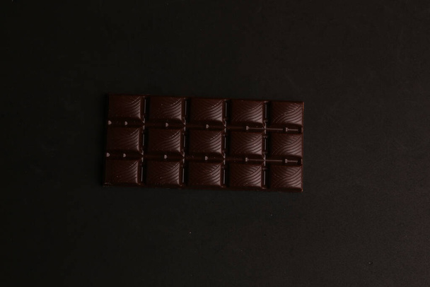 A top view of a chocolate bar on a black surface - Fotoğraf, Görsel
