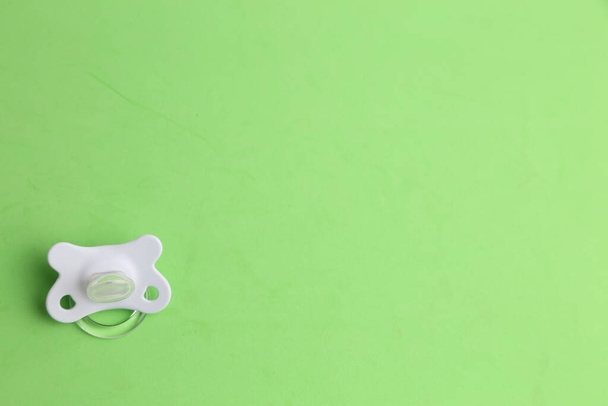 A high angle shot of a white pacifier isolated on a green surface - Foto, immagini