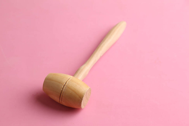 Um tiro de close-up de um martelo de madeira em um fundo rosa
 - Foto, Imagem