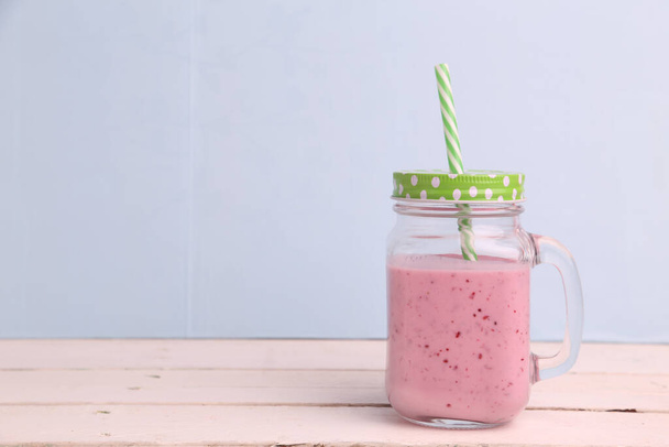 A glass jar of blackberry smoothie with a straw on wooden background - Фото, зображення