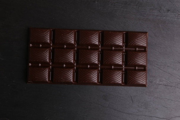 A closeup of a dark chocolate bar on a black background - Foto, Bild