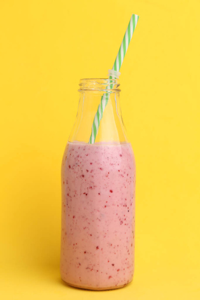 A vertical shot of blackberry smoothie in a glass bottle with a straw in it isolated on a yellow background - Fotoğraf, Görsel