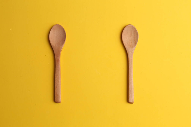 Two wooden spoons on a yellow background - Fotoğraf, Görsel