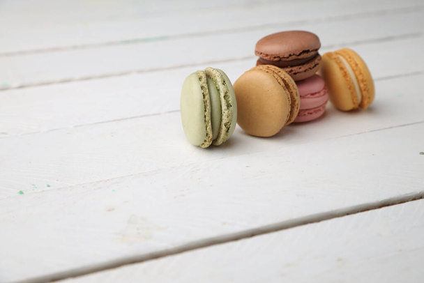 A high angle shot of a set of colorful macaroons on a white wooden surface - Foto, Bild