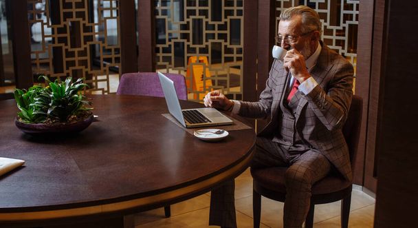 Old Businessman with laptop at coffee break in his office concept - Fotó, kép