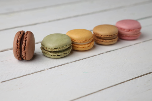 A group of colorful macarons on white wooden background - Photo, image
