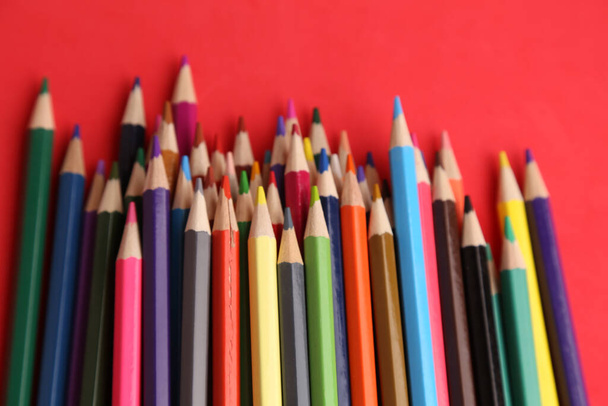 A closeup shot of colored pencils against a red background - Φωτογραφία, εικόνα