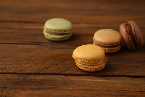 A closeup shot of delicious sweet macarons on a wooden surface - Фото, изображение