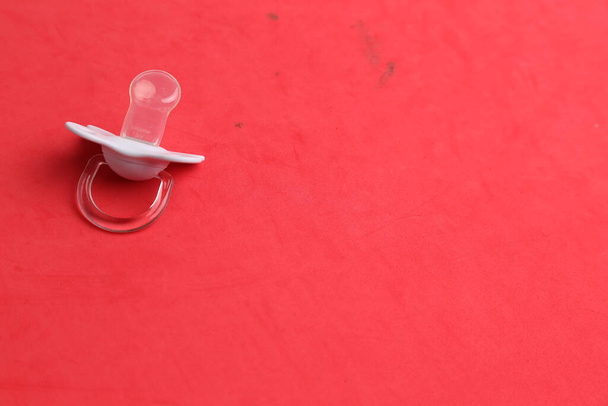 A closeup shot of a pacifier on a red background - Valokuva, kuva