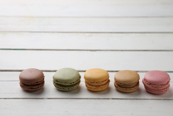 A closeup shot of colorful macaroons on a white wooden table - Фото, изображение