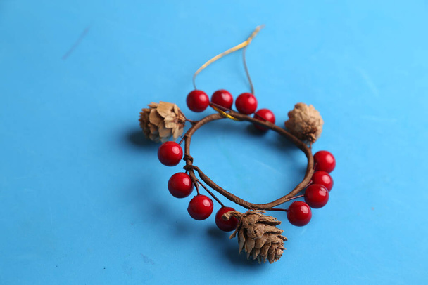 A closeup shot of a wooden trinket decorated with red fruits on the blue surface - Photo, Image