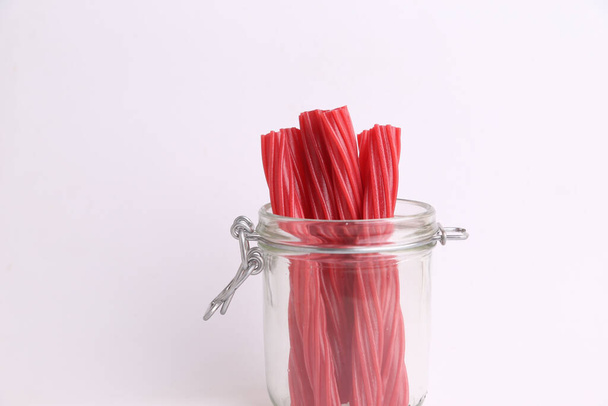 A closeup of red licorice candies in a jar isolated on a white background - Φωτογραφία, εικόνα
