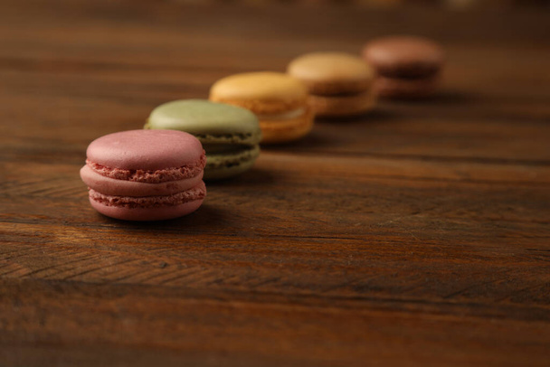 A selective focus shot of delicious and colorful macarons on a wooden surface - Fotografie, Obrázek