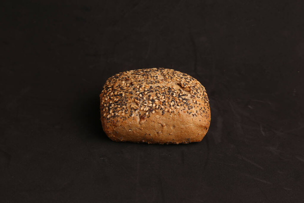 A high angle shot of a homemade bread isolated on a black surface - Photo, image