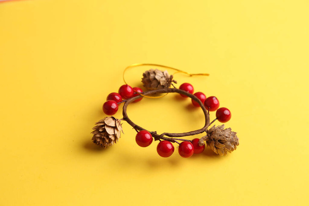 A closeup of a round ornament made of acorns and currants on a yellow background - Photo, Image