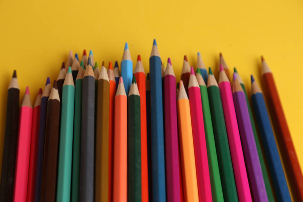 A closeup shot of colorful pencils on a yellow background - Fotó, kép
