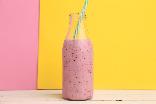 A closeup shot of a bottle of strawberry milkshake on a pink and yellow background - Фото, зображення