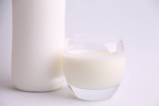 A closeup shot of a glass of milk and a plastic bottle on a white surface - Photo, Image