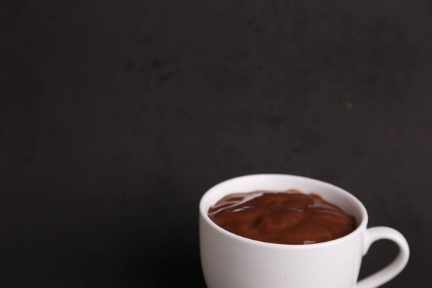 Un colpo ad alto angolo di una tazza di deliziosa cioccolata calda isolata su uno sfondo nero - Foto, immagini