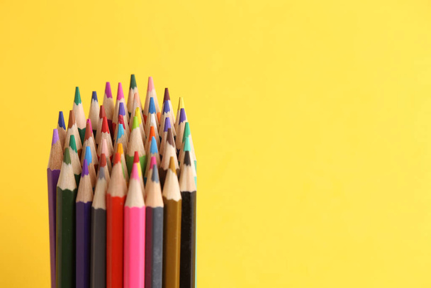 A high angle shot of the colored pencils on a yellow background - Valokuva, kuva