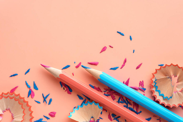 Blue and pink pencils, colored pencils shavings on pink background - 写真・画像