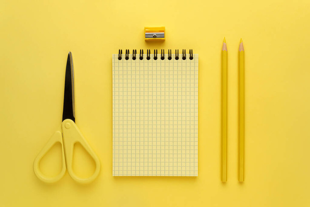 Notepad, yellow pencil and yellow scissors on a yellow background - Foto, Bild