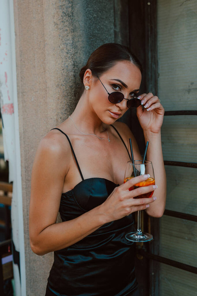 Güneş gözlüklü ve elinde kokteyl olan güzel bir kadının portresi. - Fotoğraf, Görsel