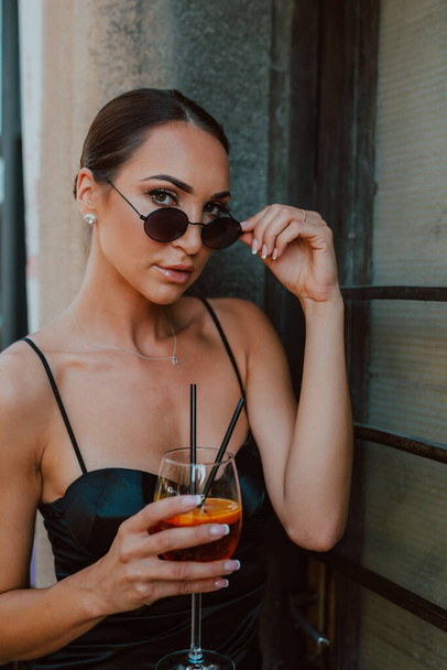Retrato de una joven hermosa mujer con gafas de sol y un cóctel en la mano - Foto, imagen