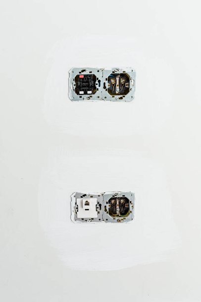 Tomas e interruptores eléctricos con el circuito interno visible en una pared durante los trabajos de renovación. - Foto, Imagen