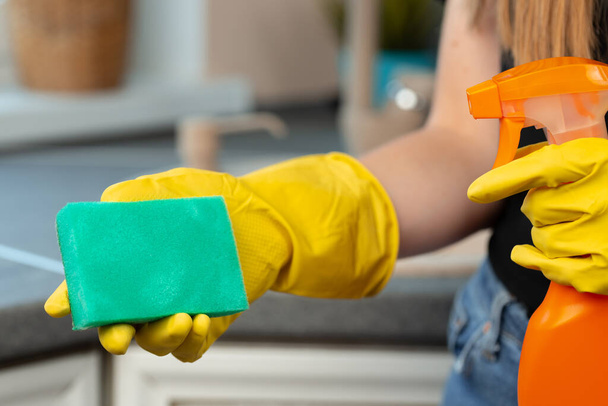Hands of a woman in yellow gloves holding green sponge - 写真・画像