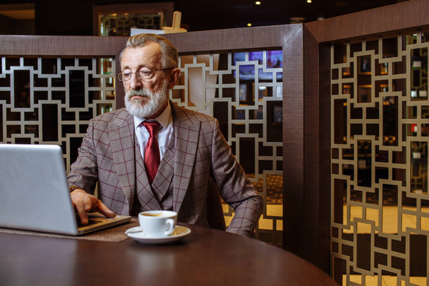Old Businessman with laptop at coffee break in his office concept - Foto, afbeelding