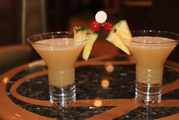 Big glass with a fruity pineapple cocktail, decorated with a wooden stirrer and fresh fruit. Cruise ship cocktail - Photo, image