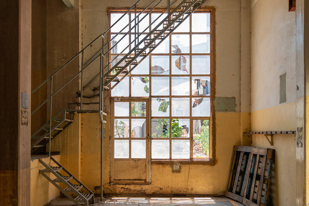 Eski kırık camlar. Sarı bir binanın içindeki metal merdivenlerle. Terk edilmiş alan - Fotoğraf, Görsel