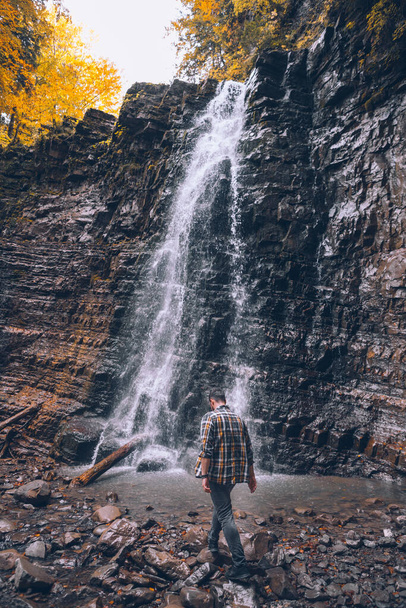 hiker man looking at autumn waterfall copy space - Photo, Image