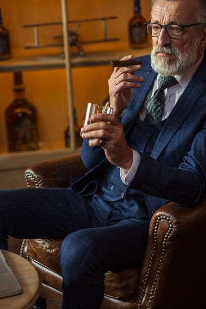 Elderly businessman with glass of whiskey and cigar on dark background - Fotoğraf, Görsel