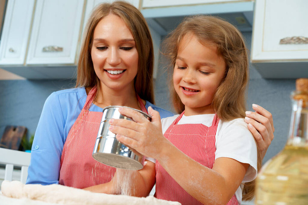 Mother and her little daughter preparing dough in kitchen - Foto, Imagem