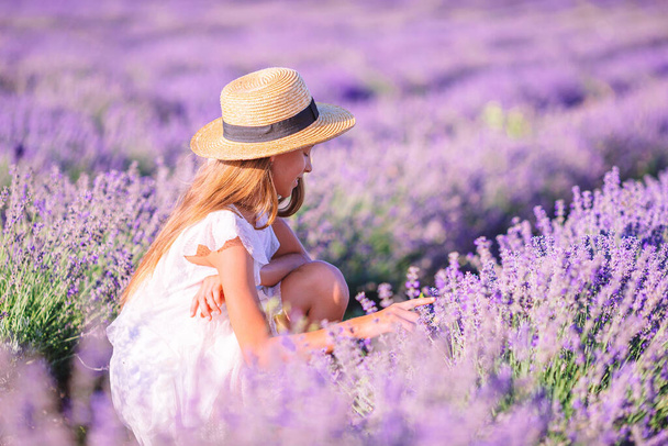 Woman in lavender flowers field in white dress and hat - Foto, imagen