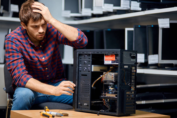 unhappy pensive man looking confused repairing hardware - Foto, afbeelding