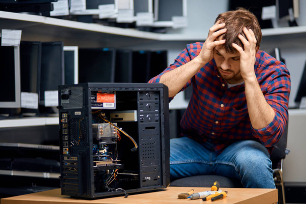 Frustrated young man due to broken system unit - Фото, изображение