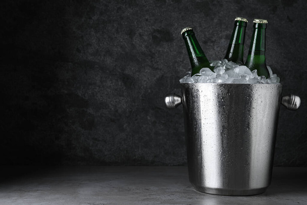 Metal bucket with beer and ice cubes on grey table. Space for text - Fotó, kép