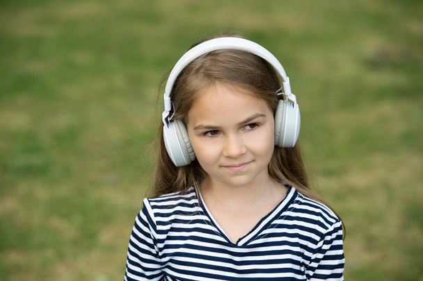 Face the music. Little girl listen to music outdoors. Small child wear headphones playing music. New technology. Modern life. Summer vacation. Fun and entertainment. Hear it - Fotó, kép