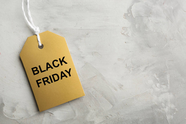 Top view of blank golden tag on light grey stone background, space for text. Black Friday concept - Foto, imagen