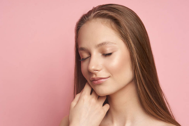 Beauty makeup. Portrait of a young girl with natural make-up on a pink background - Photo, Image