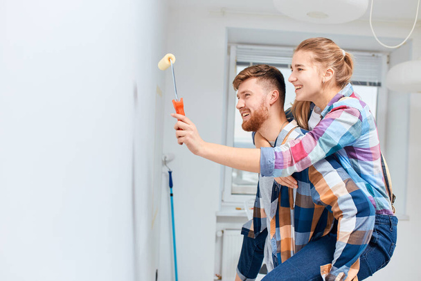 Young couple painting walls and having fun in their new house. - Photo, image